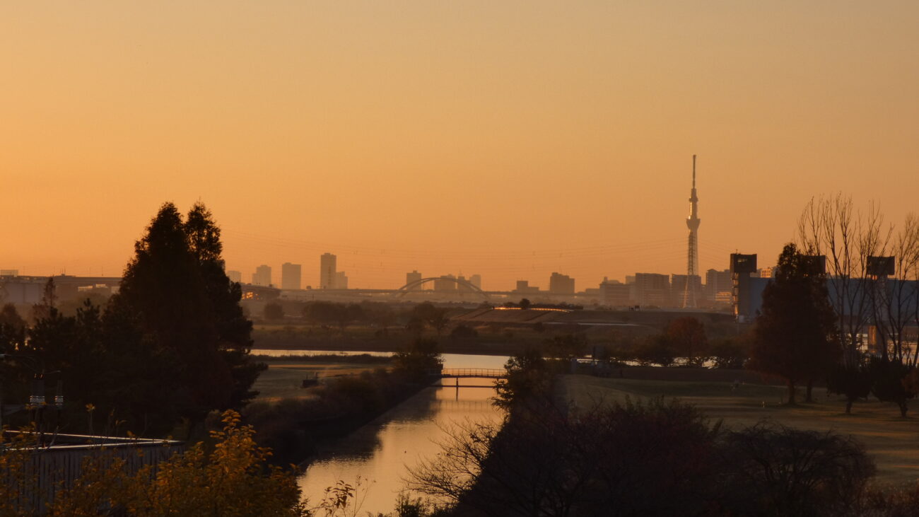 Tokyo Peace: A daily reflection photo of the Tokyo Skytree and city skyline at sunrise over a quiet river.