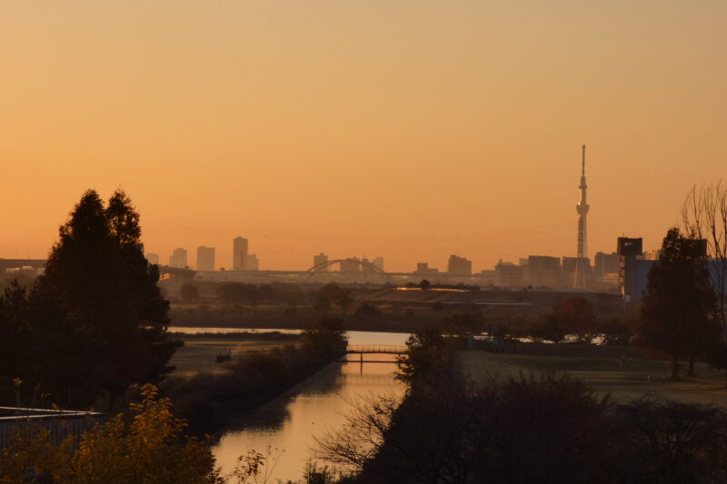 Tokyo Peace: A daily reflection photo of the Tokyo Skytree and city skyline at sunrise over a quiet river.