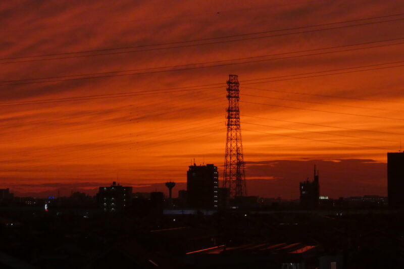 a vibrant, fiery red-orange sunset over a city skyline.