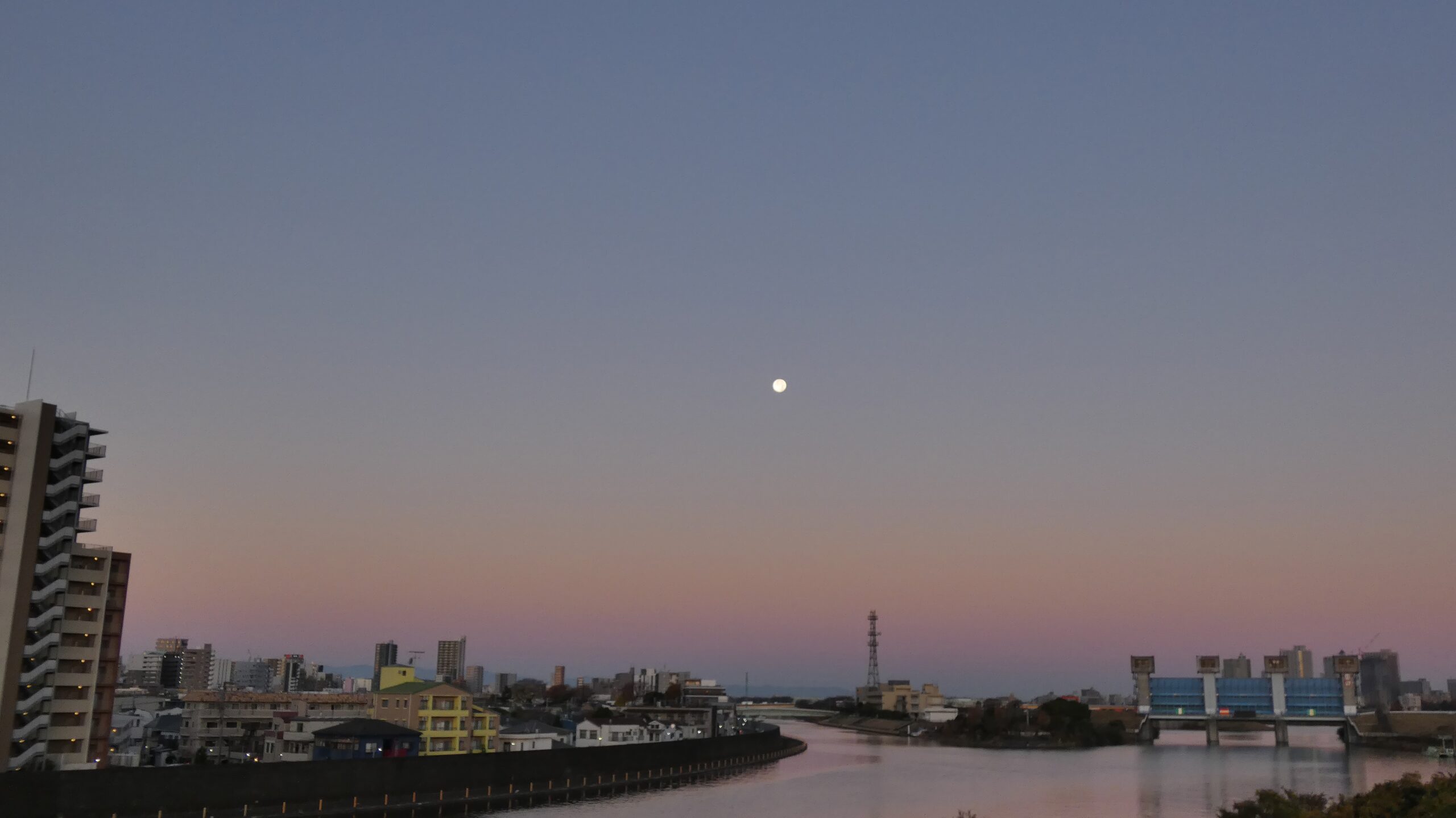 Quiet moonrise over Tokyo river at dawn, soft light breaking through the night.