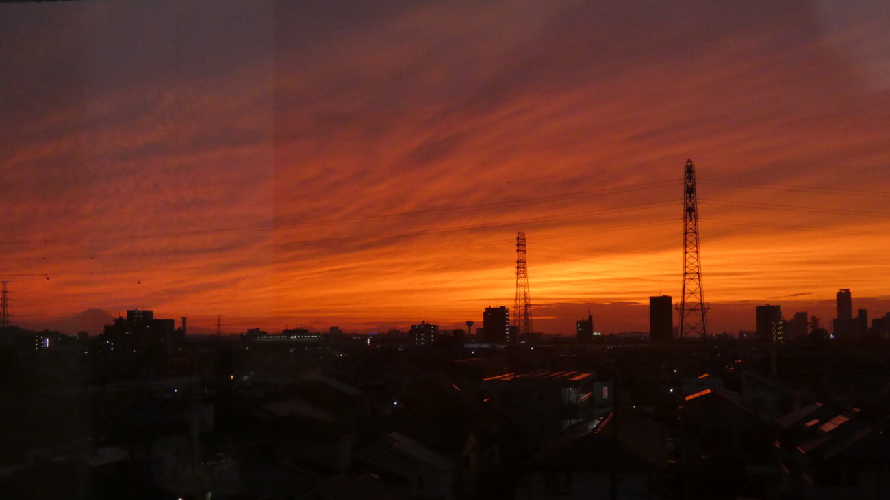 Dramatic orange sunset over a Tokyo cityscape illustrating the urgency of faith and why we dare not wait to repent.