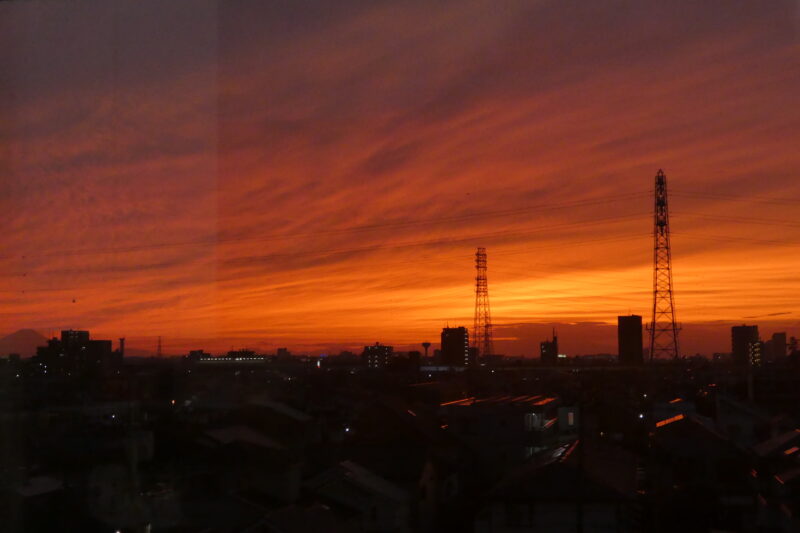 Dramatic orange sunset over a Tokyo cityscape illustrating the urgency of faith and why we dare not wait to repent.